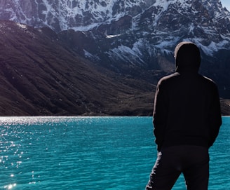 a man standing on the edge of a cliff overlooking a lake