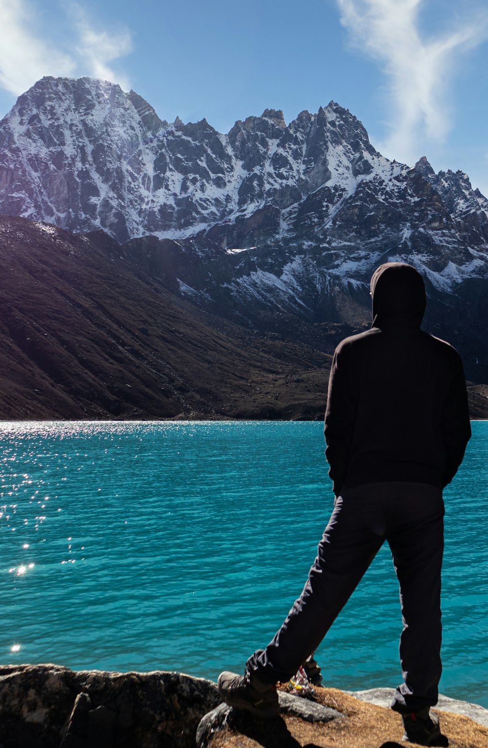 a man standing on the edge of a cliff overlooking a lake