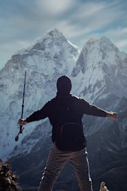 a man holding a rifle while standing on top of a mountain