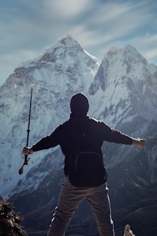 a man holding a rifle while standing on top of a mountain