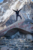 A happy climber holding up a ‘summit achieved’ sign with Kinabalu’s scenic ridge behind.