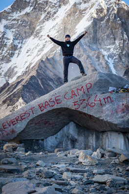 A happy climber holding up a ‘summit achieved’ sign with Kinabalu’s scenic ridge behind.