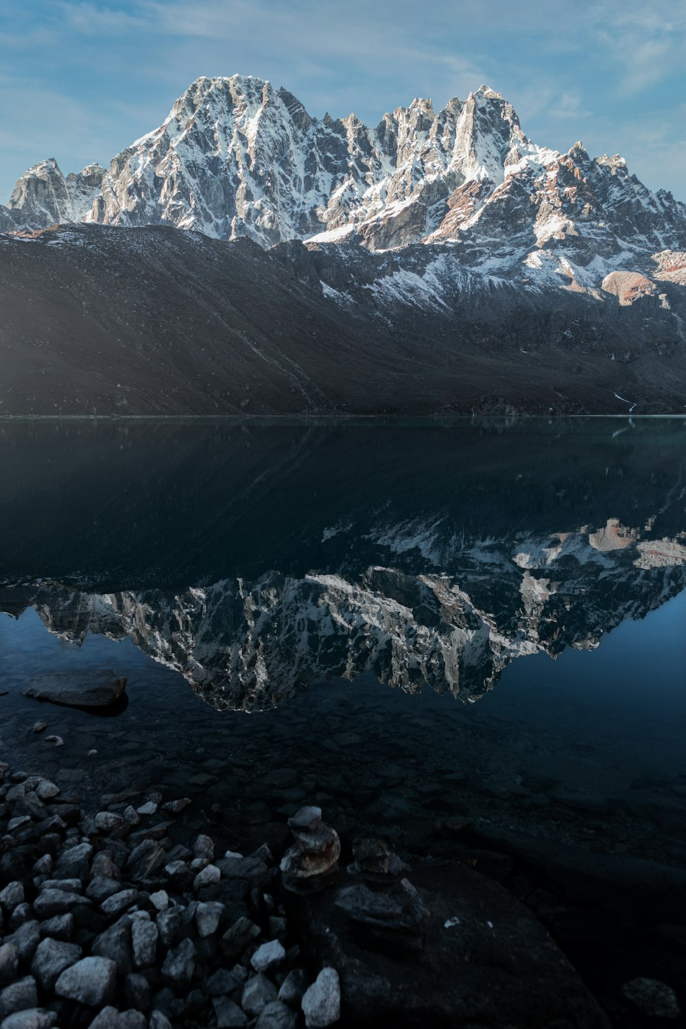 a mountain range is reflected in the still water of a lake