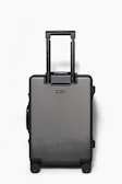 A sleek black suitcase with expandable compartments open on a wooden floor.