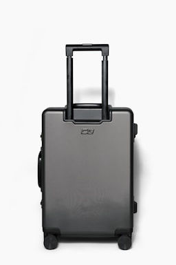 A sleek, modern suitcase with an expandable compartment, standing against a bright backdrop.