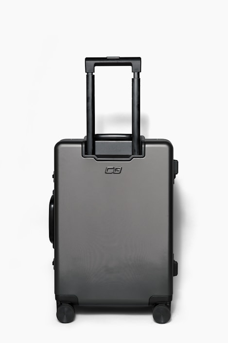 A sleek, modern hardside suitcase in a travel setting.