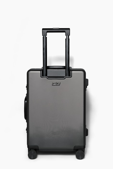 A sleek, modern hard-shell suitcase standing upright on a city sidewalk.