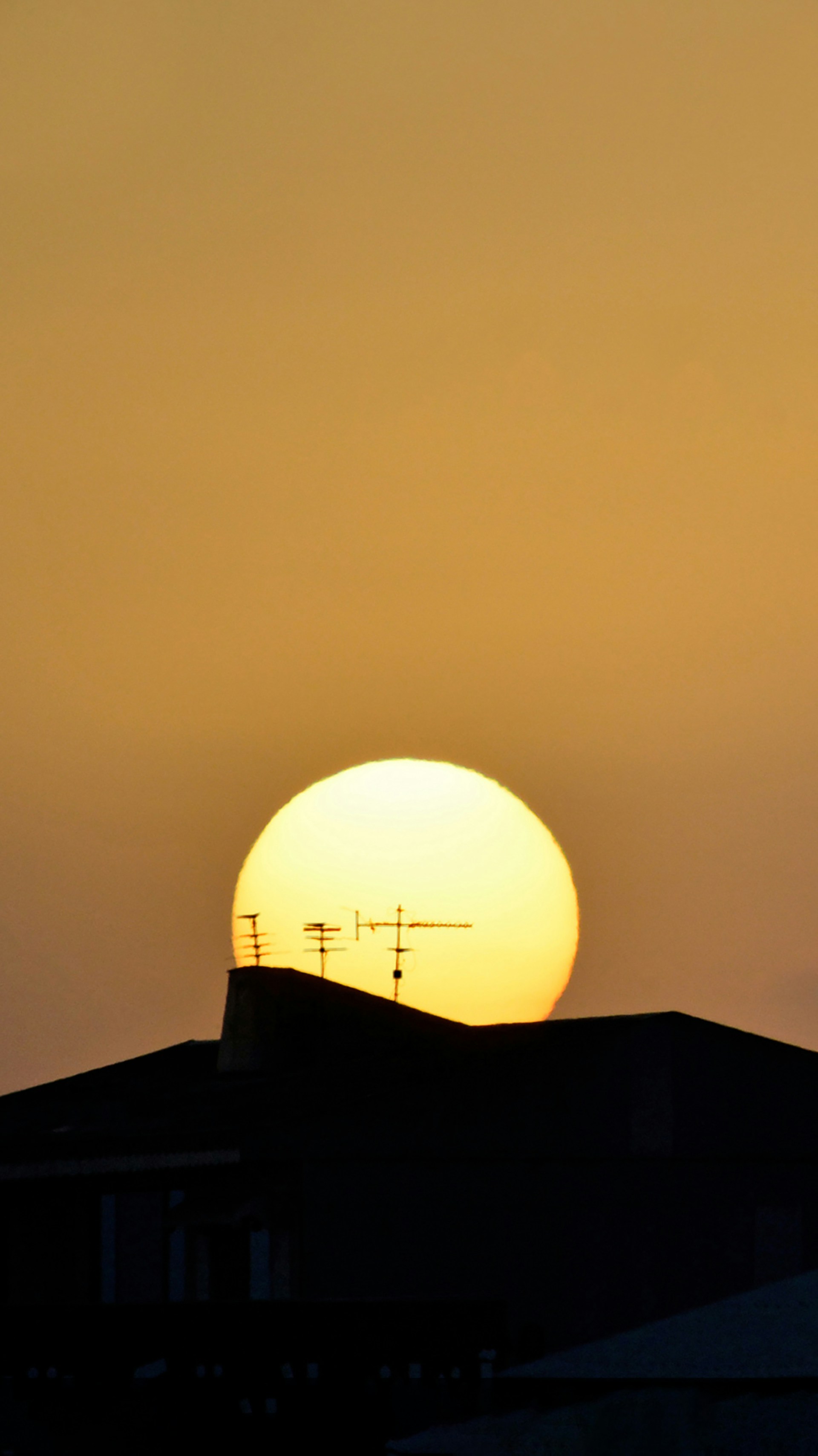 the sun is setting behind a building with a clock tower