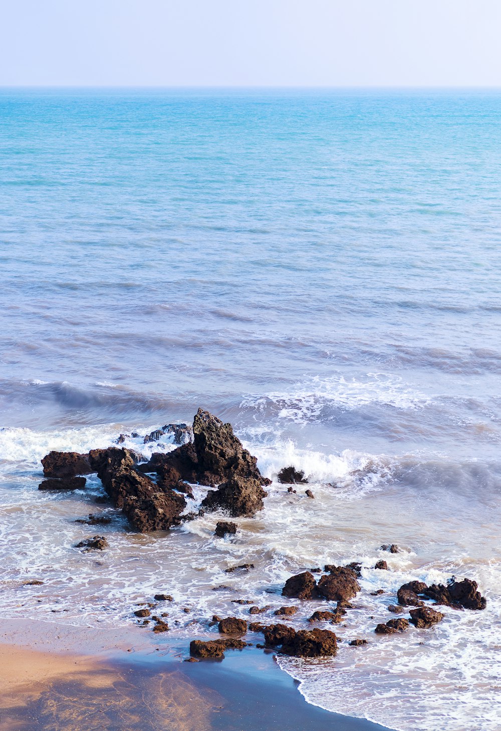 a rocky beach with a body of water in the background