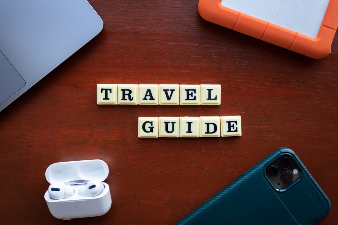 a wooden table topped with a cell phone and ear buds, Travel Guide Words