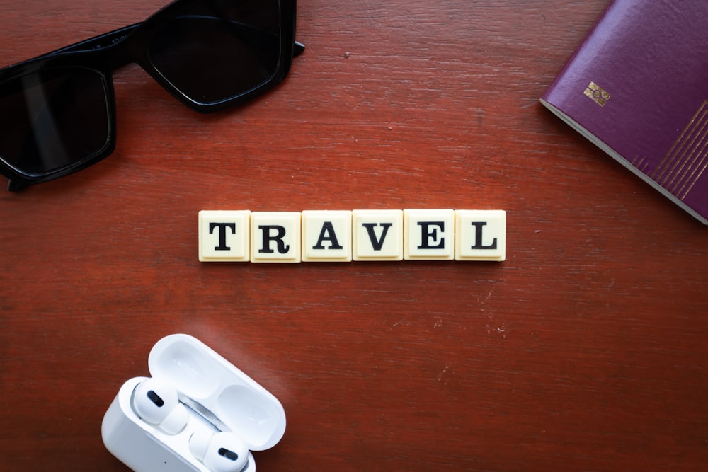 the word travel spelled with scrabbles on a wooden table