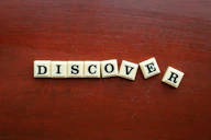 the word discovery spelled with scrabble letters on a wooden surface
