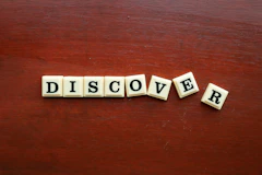 the word discovery spelled with scrabble letters on a wooden surface