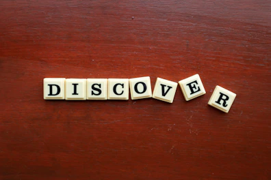the word discovery spelled with scrabble letters on a wooden surface