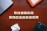 Wooden tiles with letters spelling out 'ONLINE LANGUAGES' are arranged neatly on a wooden surface. Surrounding the tiles, there are a laptop, a hard drive, a smartphone, and wireless earphones.