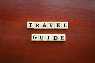 the word travel guide spelled with scrabble tiles