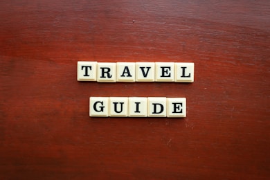 the word travel guide spelled with scrabble tiles
