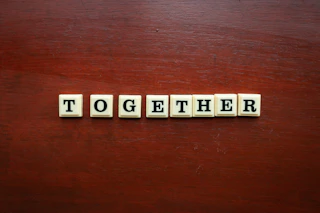 the word together spelled with scrabble tiles on a wooden surface