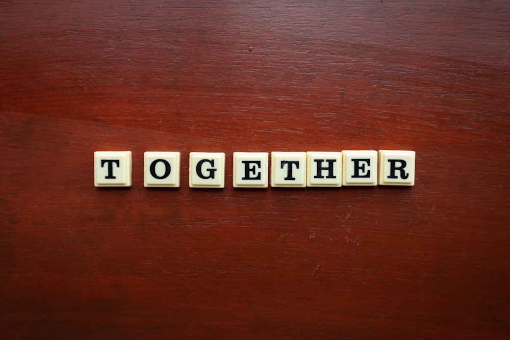 the word together spelled with scrabble tiles on a wooden surface