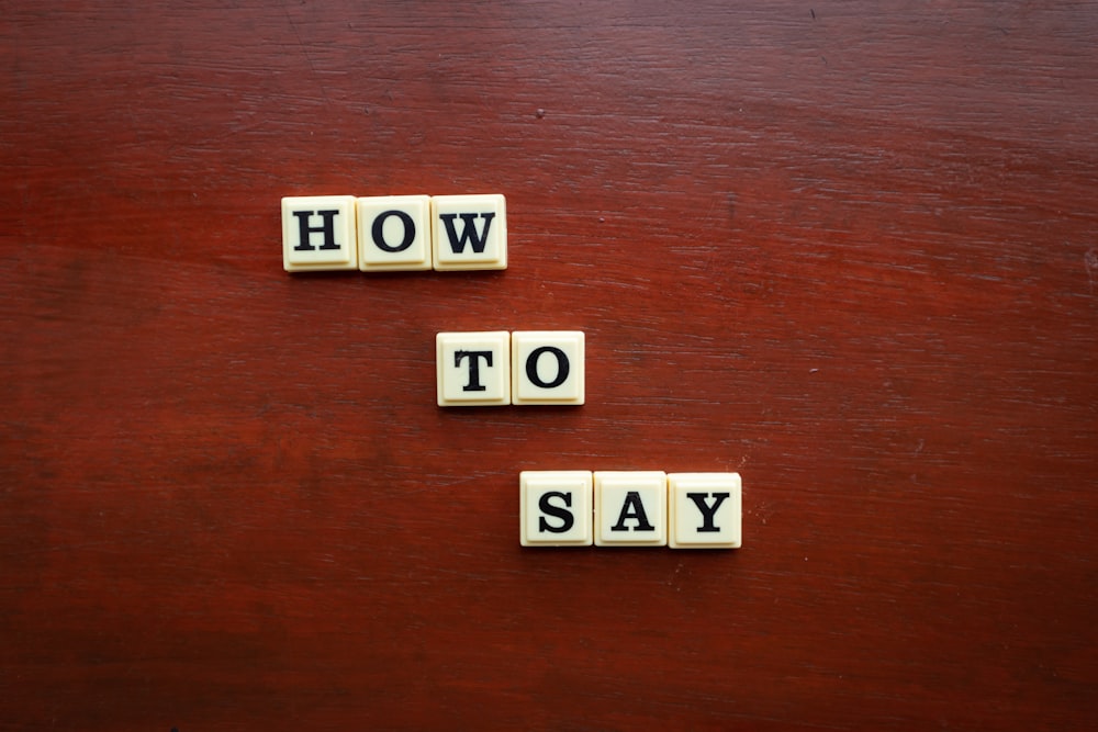 scrabble tiles spelling how to say on a wooden surface