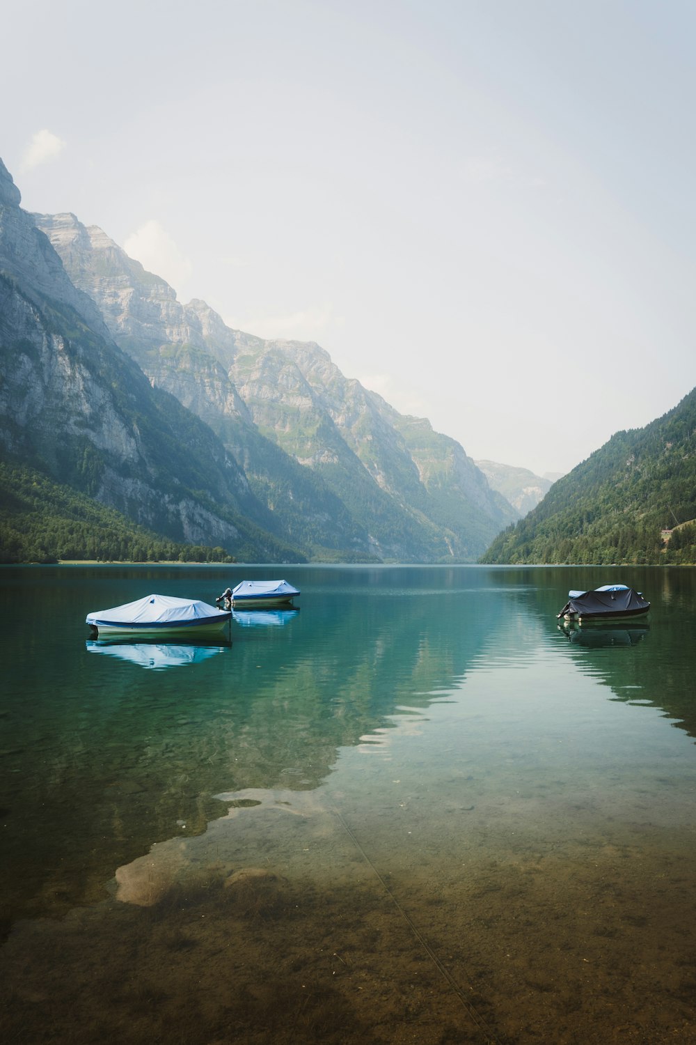 two boats floating on a lake surrounded by mountains