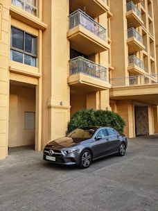 Red sedan car parked in front of a modern house.