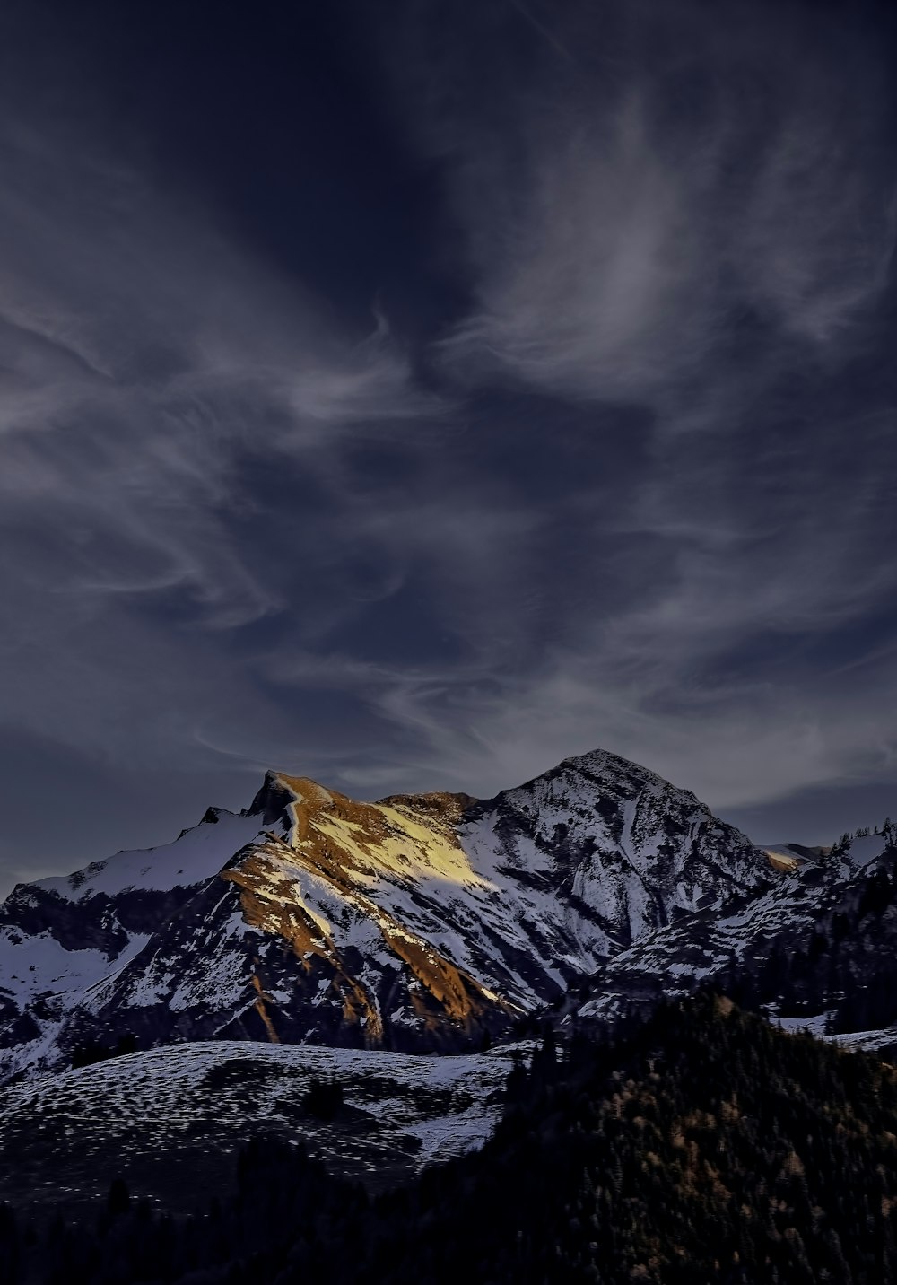 a snow covered mountain under a cloudy sky