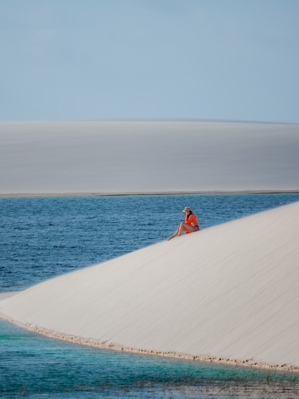 a person sitting on top of a sand dune