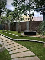 A scenic backyard with a manicured lawn, palm trees, and a stone pathway.