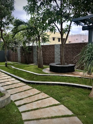 A scenic backyard with a manicured lawn, palm trees, and a stone pathway.