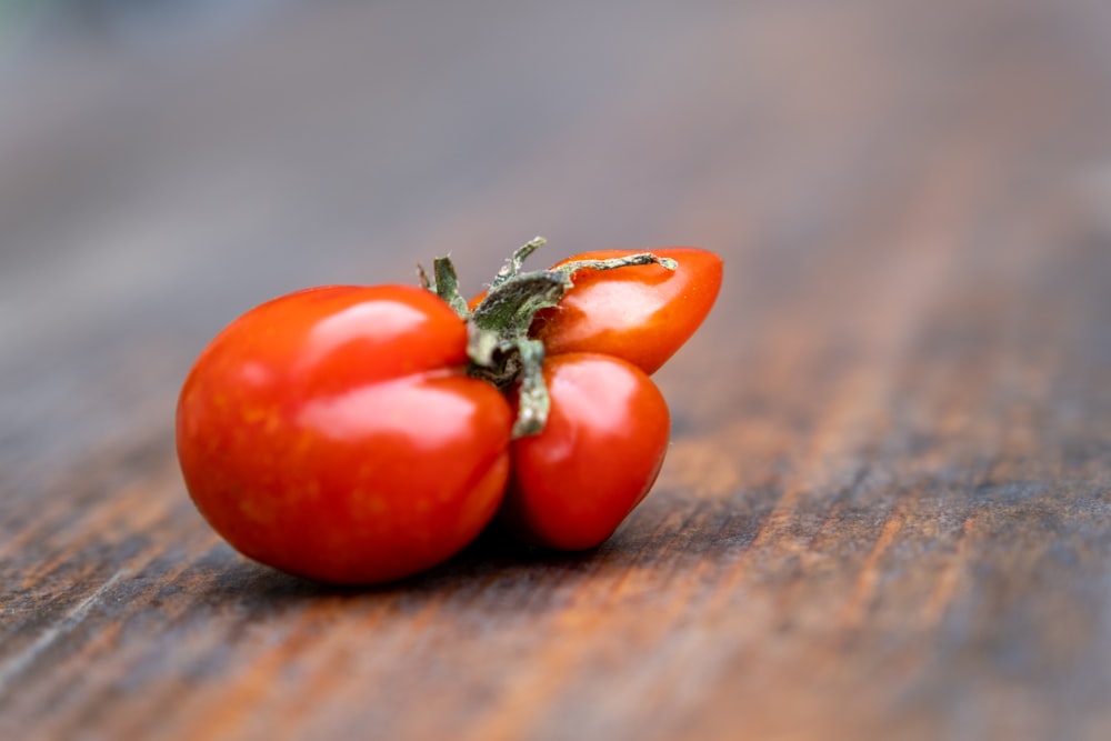 a couple of tomatoes sitting on top of a wooden table