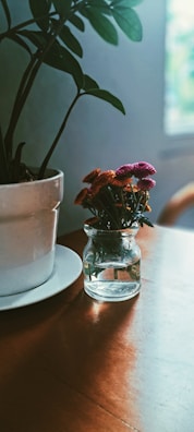 A small vase of fresh flowers on a wooden table amid soft natural light.