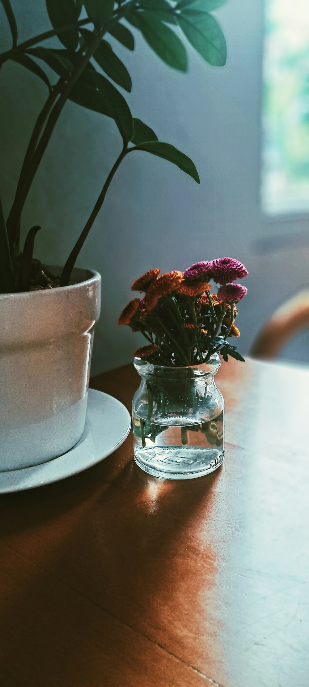 eine Vase mit Blumen auf einem Tisch neben einem Teller