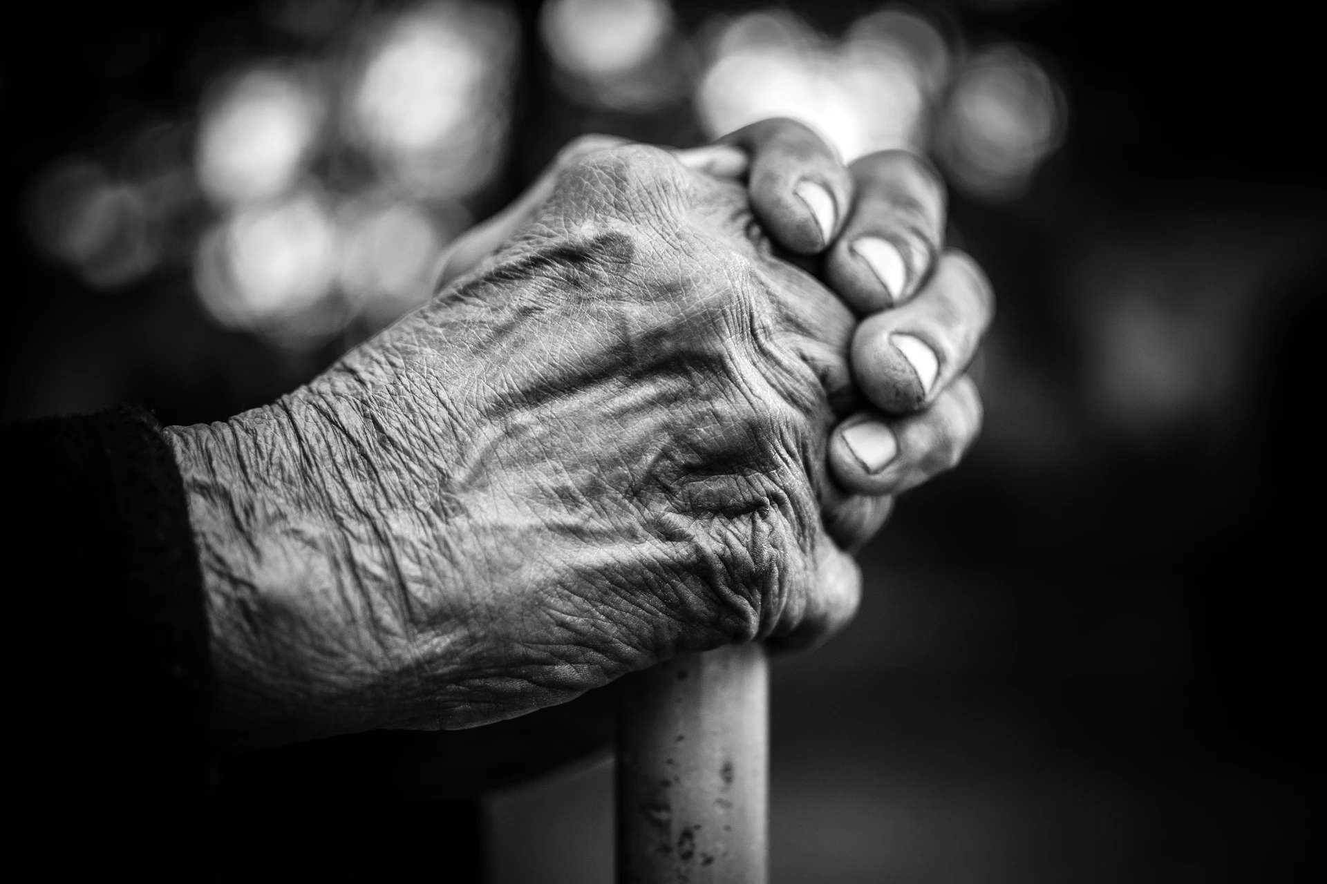 An intimate black and white close-up of an elderly man's weathered hands, telling stories of a life well-lived through every line and crease.