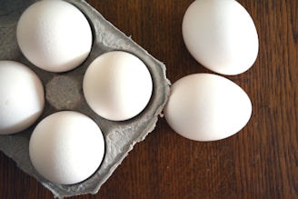 six eggs in a carton on a wooden table