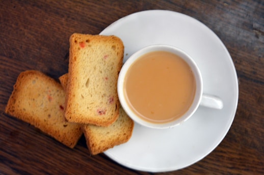 a white plate topped with slices of bread next to a cup of tea