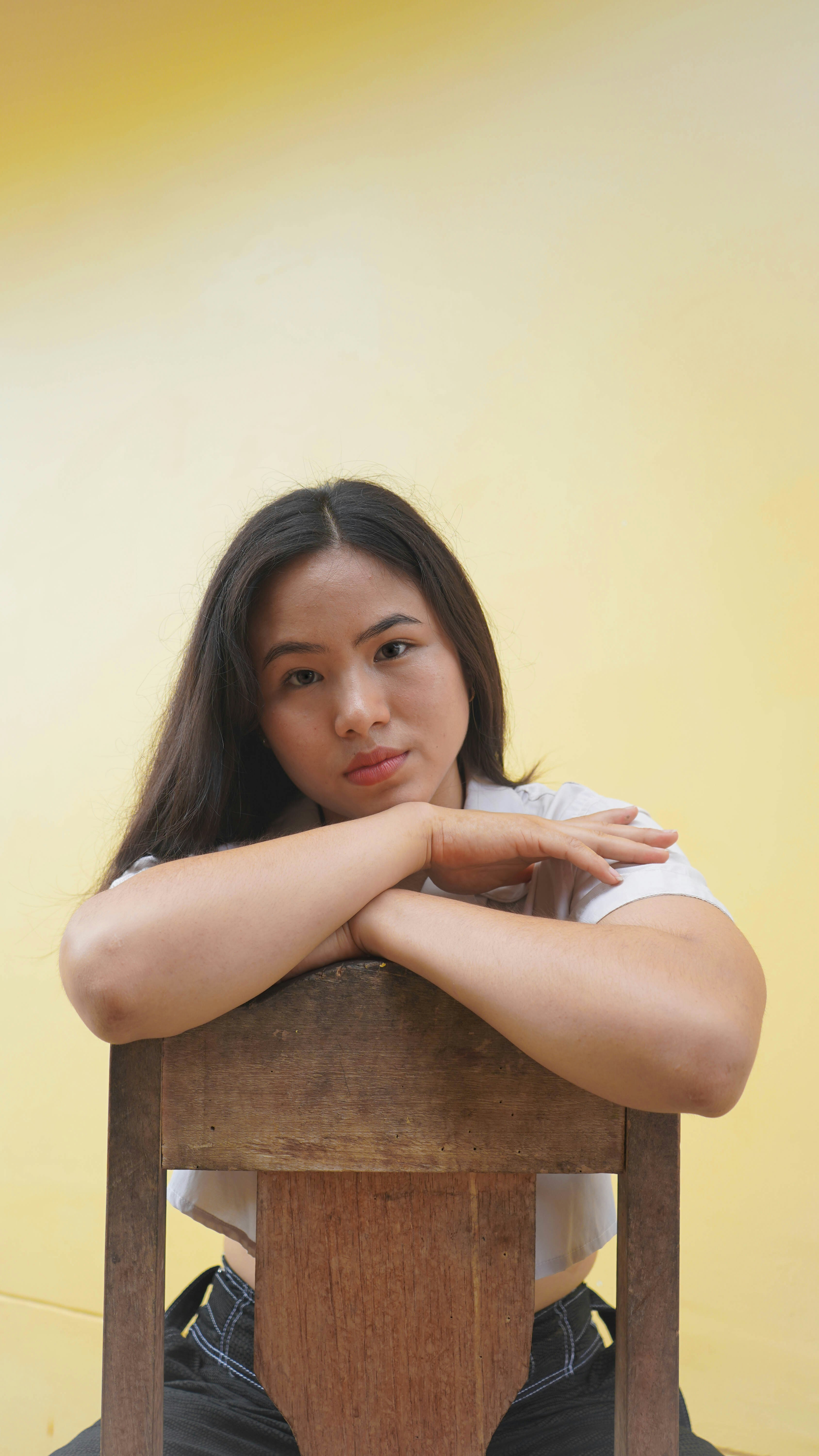 a woman sitting on top of a wooden chair