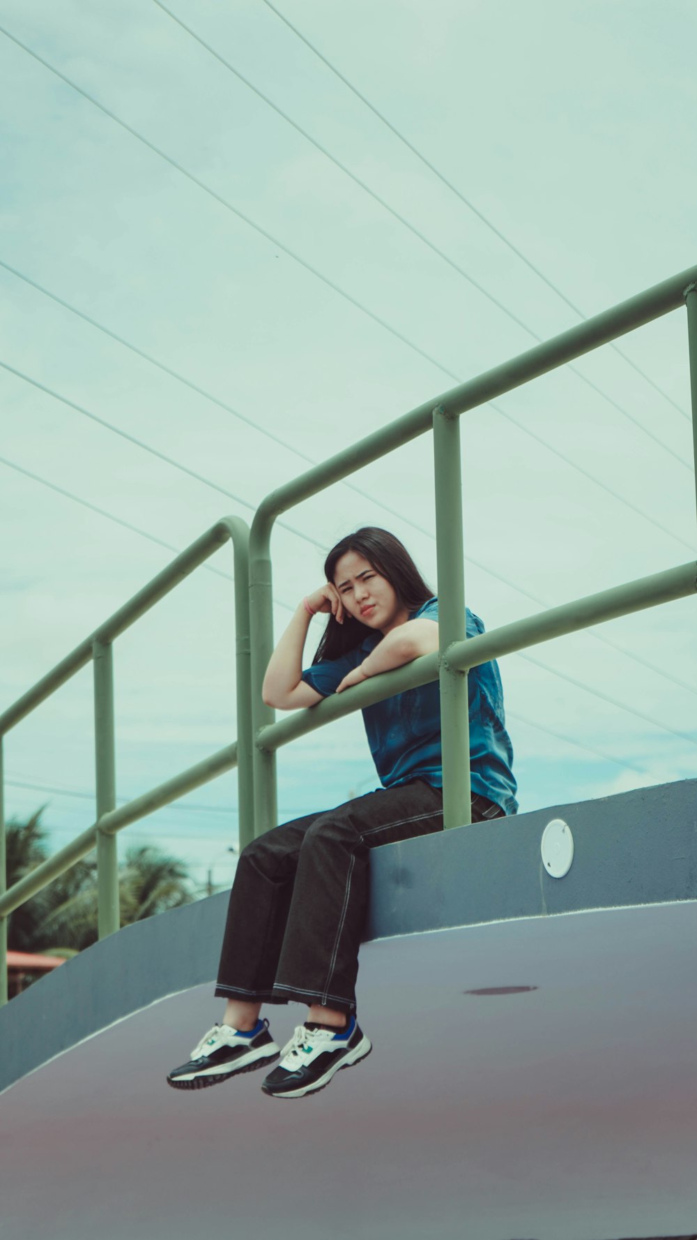 a woman sitting on top of a metal rail