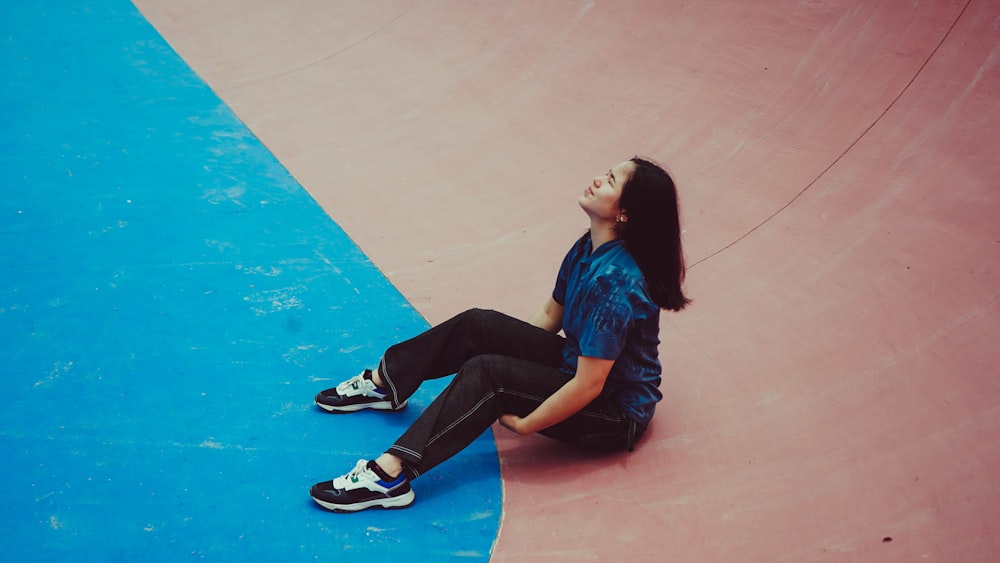 a girl sitting on the ground at a skate park