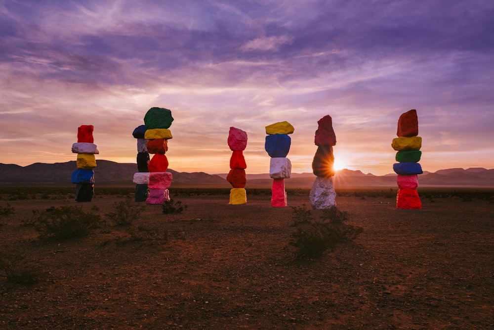 a group of colorful sculptures sitting on top of a dirt field