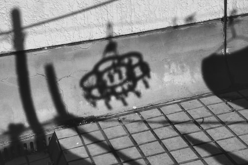 Monochrome sculpture casting long shadows on textured wall