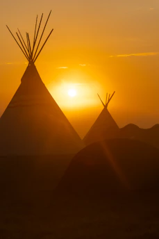 A serene sunrise over tribal lands with traditional symbols subtly visible in the landscape.