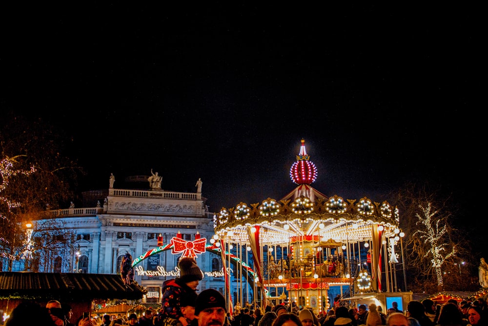 a crowd of people standing around a carousel at night