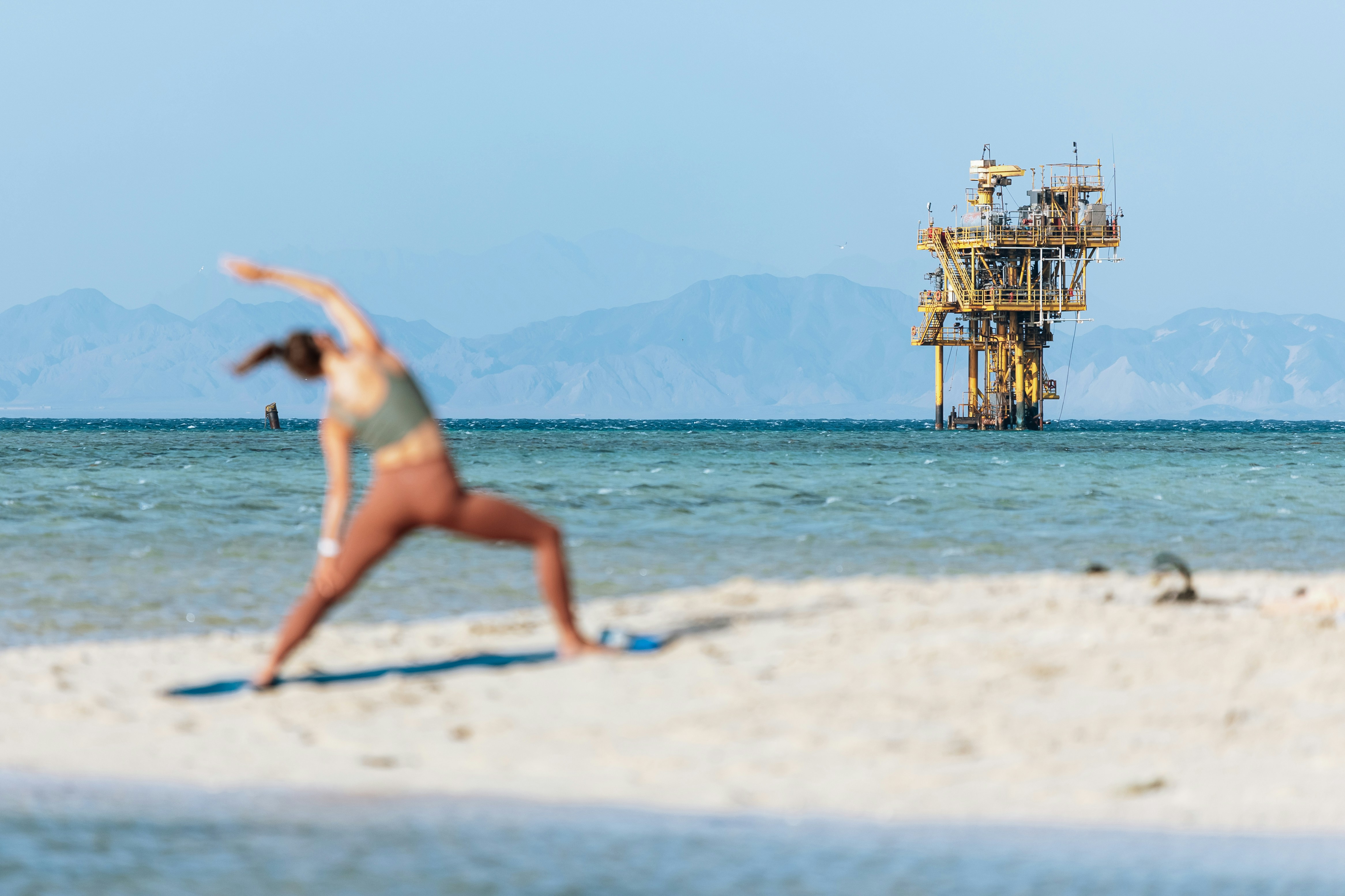 a woman in a bikini doing yoga on the beach