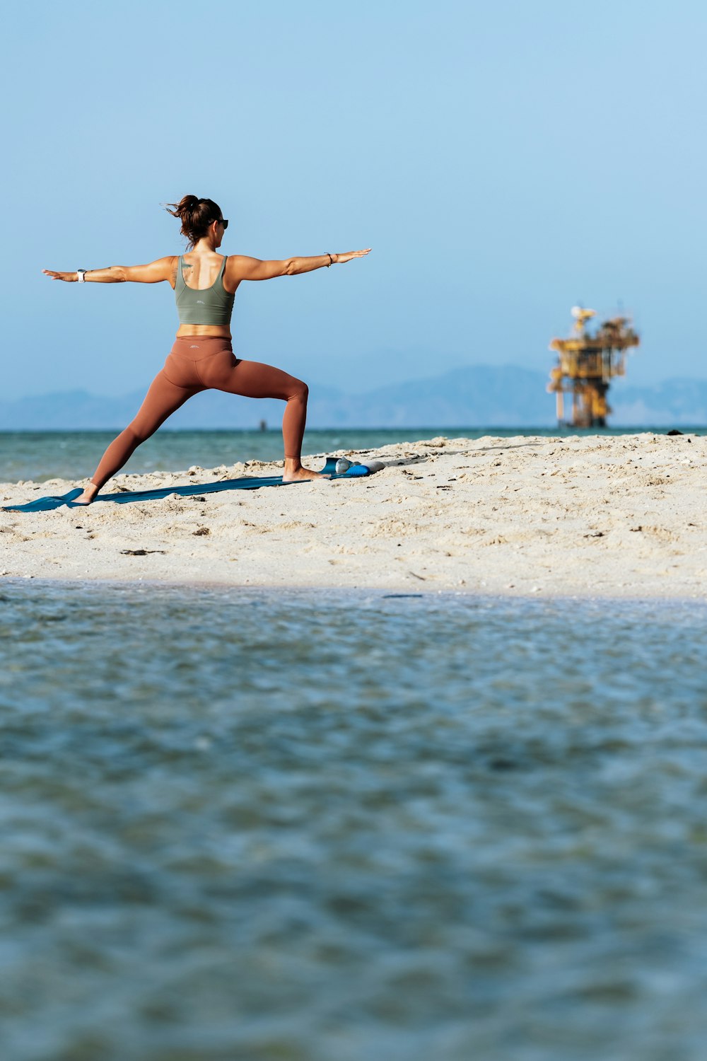 a woman is doing yoga on the beach