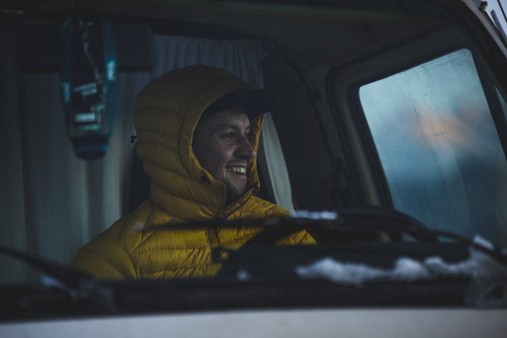 a man in a yellow jacket sitting in a car