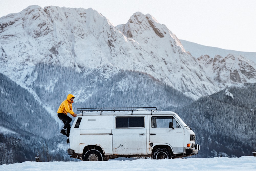 a man sitting on top of a van in the snow