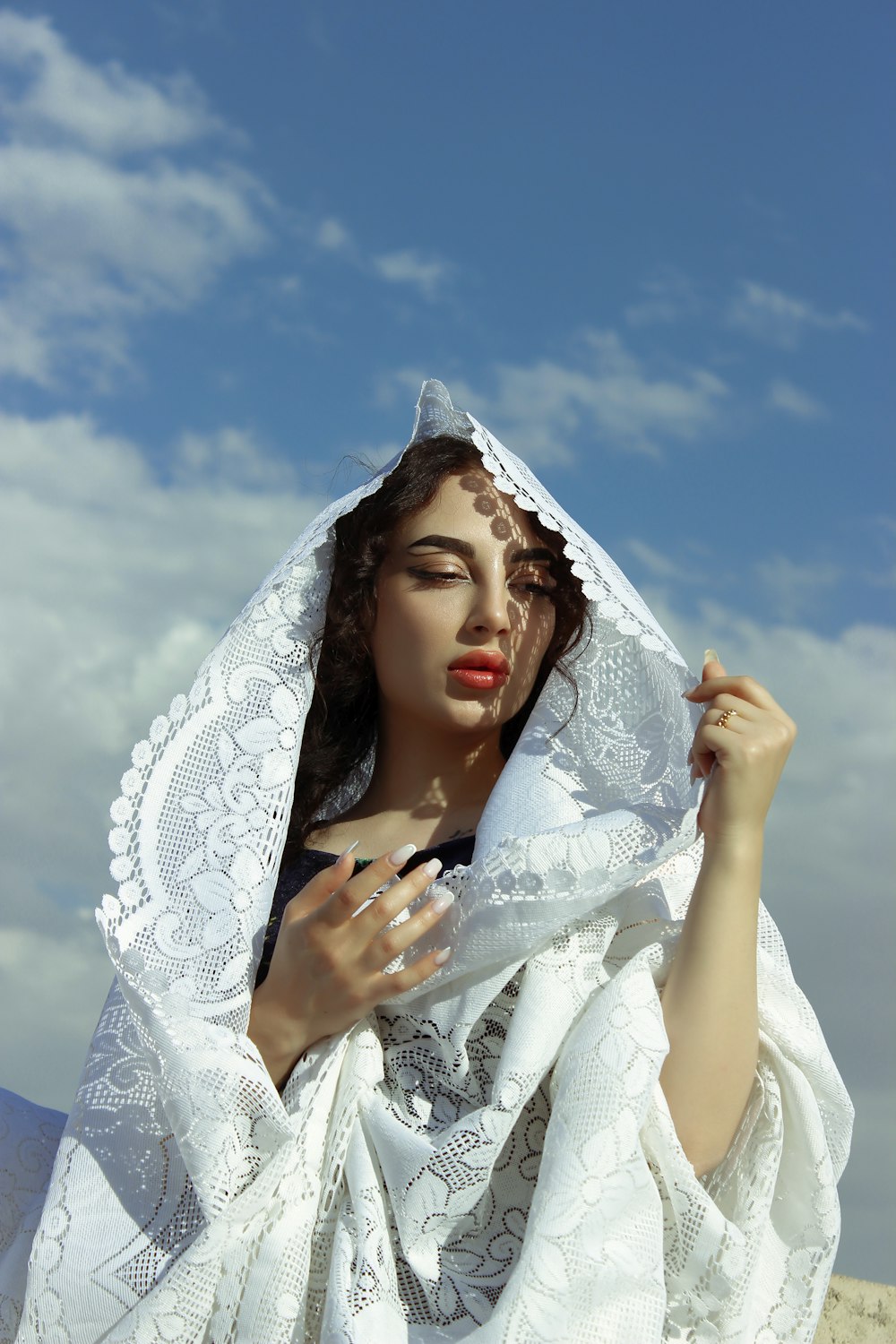 a woman wearing a white shawl and holding a cigarette