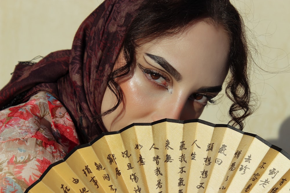 a woman holding a fan with writing on it