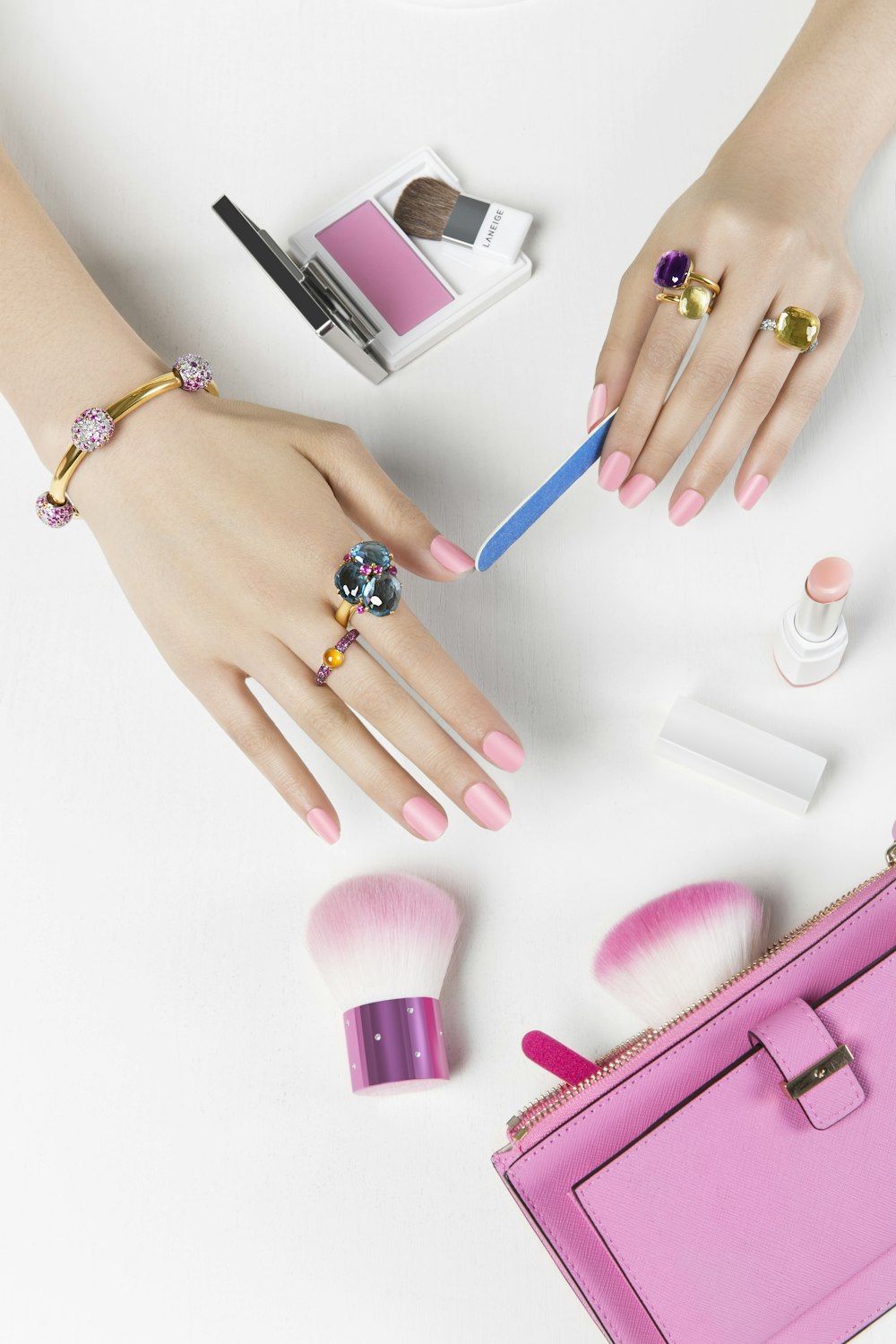 a woman's hands with pink manicures and makeup